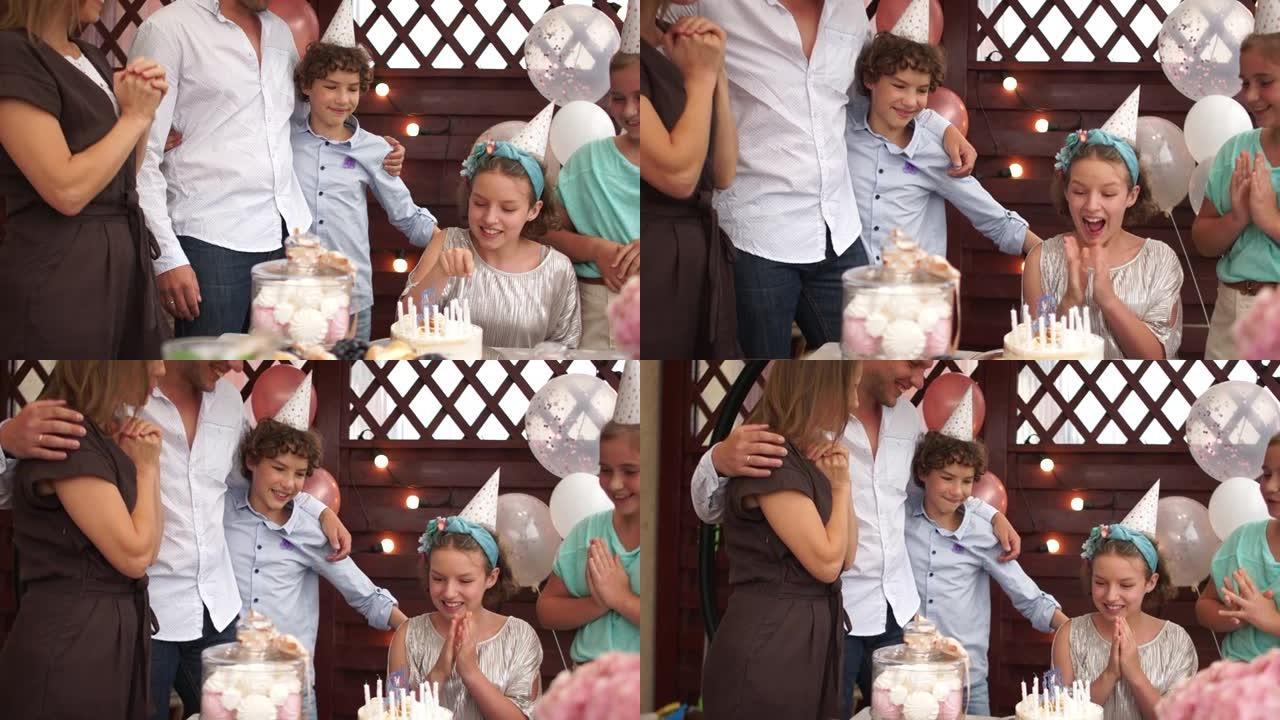 欢快的生日女孩少年在她的生日蛋糕上数蜡烛。家庭祝贺女儿，户外儿童生日庆祝活动，餐饮概念