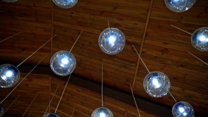 现代天花板照明。棕色背景，白色电线上悬挂着漂亮的圆形玻璃球灯。房间的豪华设计。