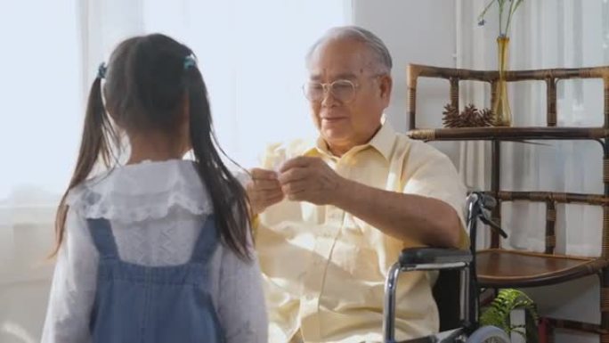 老人孤独地坐在轮椅上生病和孙女奔跑抱着纸鸟玩耍