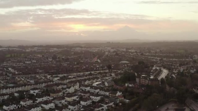 空中跟踪拍摄的早晨城市城市景观住房，道路和交通下，在英国五颜六色的早晨天空