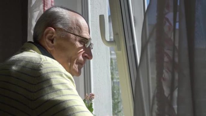 戴眼镜的老人欣赏站在窗前的城市景观