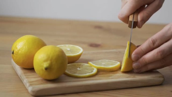 女手在木砧板上用刀将柠檬切成圆片