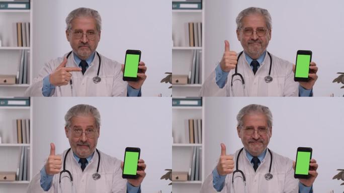 老年男性医生拿着带有绿屏色度键的智能手机，用手指指着它，并做拇指向上的手势。穿着白色医用外套的医生坐