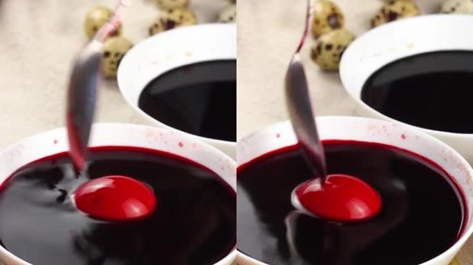 高加索儿童用金属勺子画一个复活节彩蛋，然后将其浸入带有红色染料的白色碗中。复活节假期的概念。垂直视频