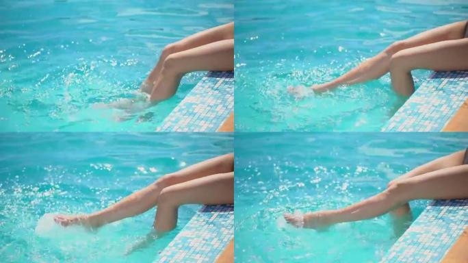 在炎热的阳光明媚的日子里，一个面目全非的女孩坐在泳池边，用脚泼水。顽皮的年轻女子在夏天用腿泼水。节假