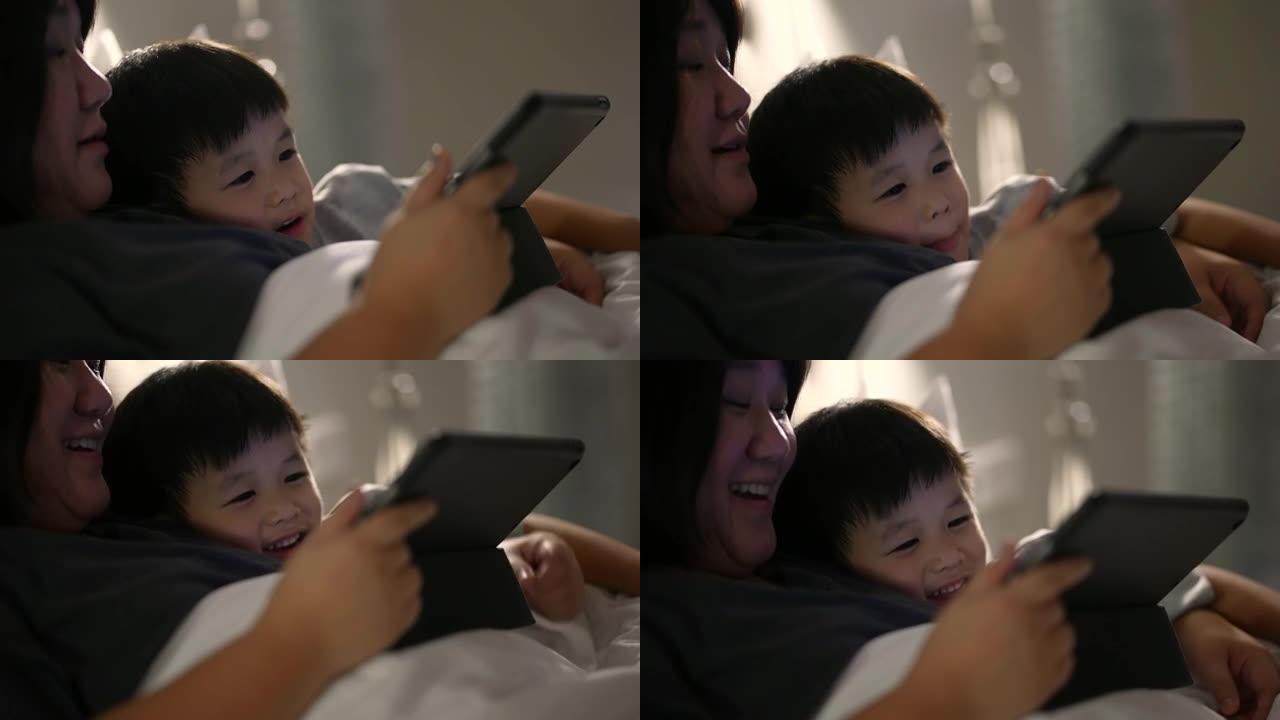 亚洲孩子和母亲使用数字平板电脑玩游戏。家庭时间时刻的概念