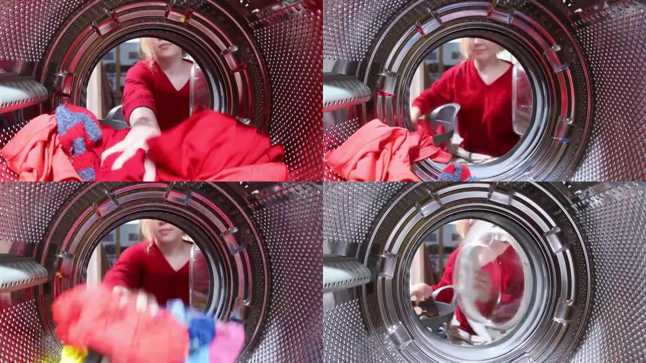 从洗衣机滚筒内看，一名年轻女子从baske装载脏衣服。从洗衣机里拿出衣服。