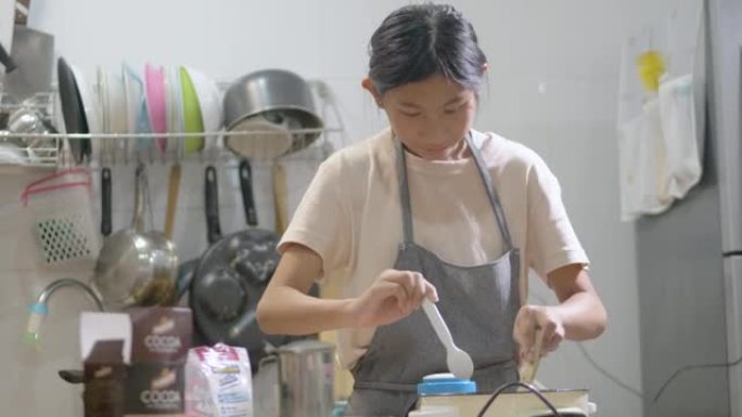 亚洲儿童穿着围裙在厨房一起制作焦糖爆米花，周末生活方式概念。