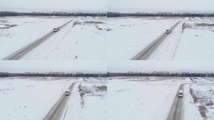 无人机飞到公共汽车后面。冬季道路以白雪覆盖的田野为背景，鸟瞰。西伯利亚针叶林冬季的油田