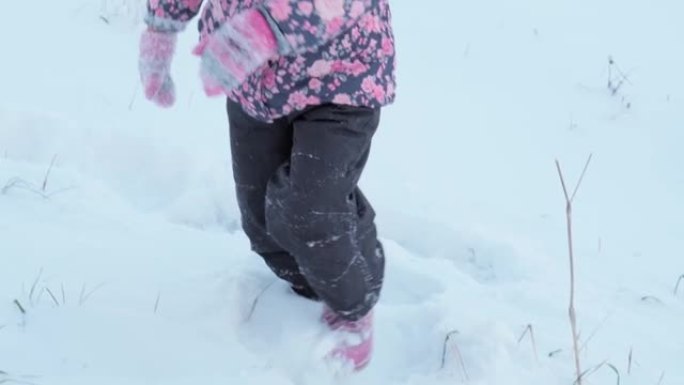 冬天，假期，游戏，家庭概念-慢动作近距离的孩子在深雪中奔跑。孩子们的脚踩在雪道上。寒冷季节的降雪中穿