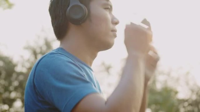 亚洲运动员男子戴着耳机准备在公园跑步锻炼和慢跑。