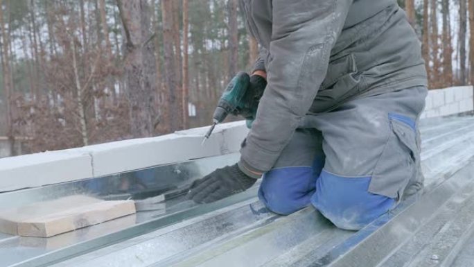 屋顶工用螺钉固定屋顶的镀锌铁片。
