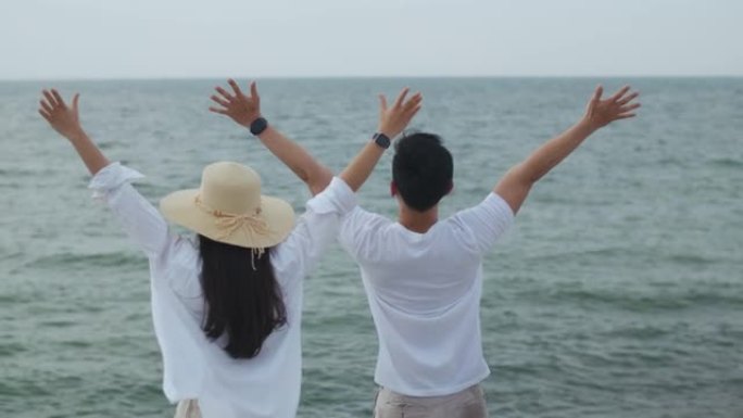 恋爱中的年轻夫妇在假期周末举起双臂庆祝成功。浪漫情侣在海滩度假旅行。
