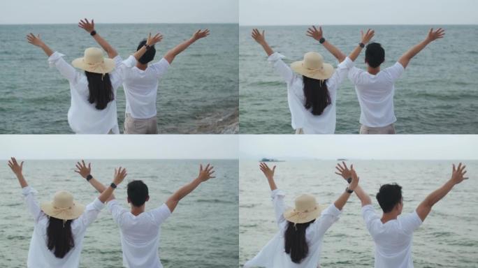 恋爱中的年轻夫妇在假期周末举起双臂庆祝成功。浪漫情侣在海滩度假旅行。