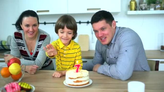 厨房里有趣的小男孩和父母一起玩水果。非常可爱的男孩用蛋糕庆祝他的生日 & 快乐的父亲和母亲。迷人的父