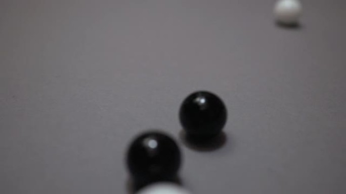 许多黑白球在灰色表面上碰撞和滚动