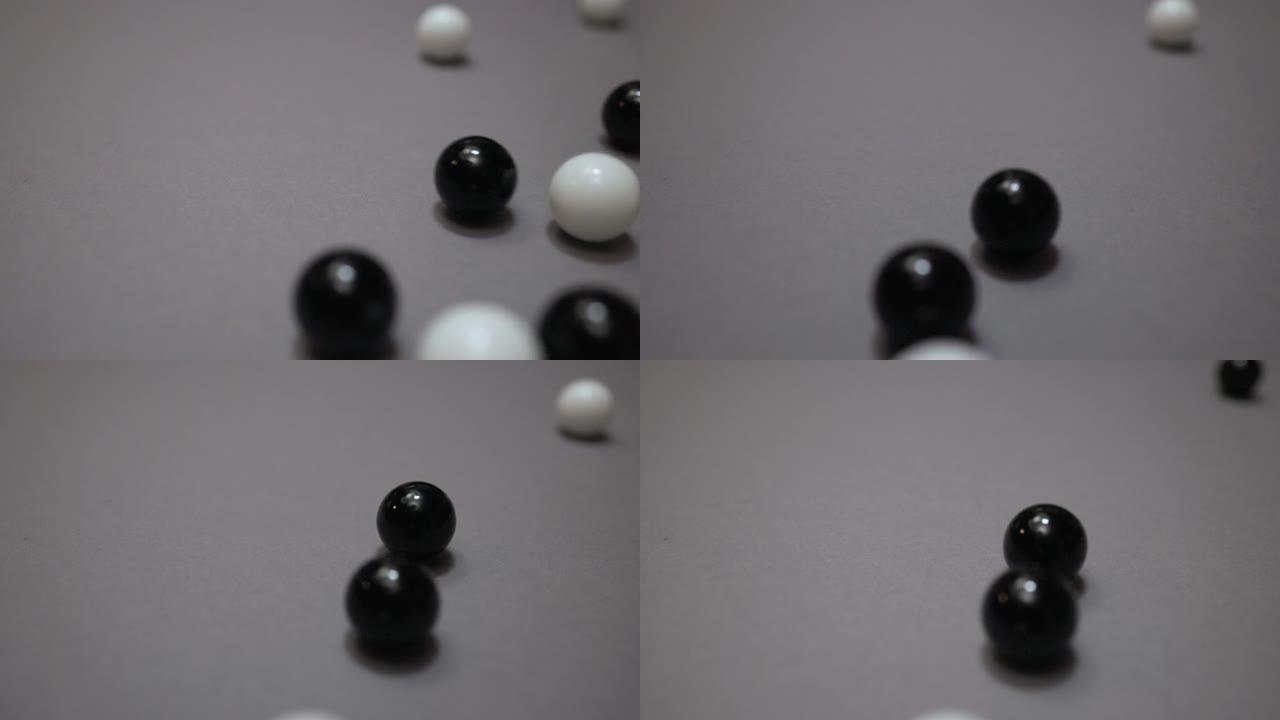 许多黑白球在灰色表面上碰撞和滚动