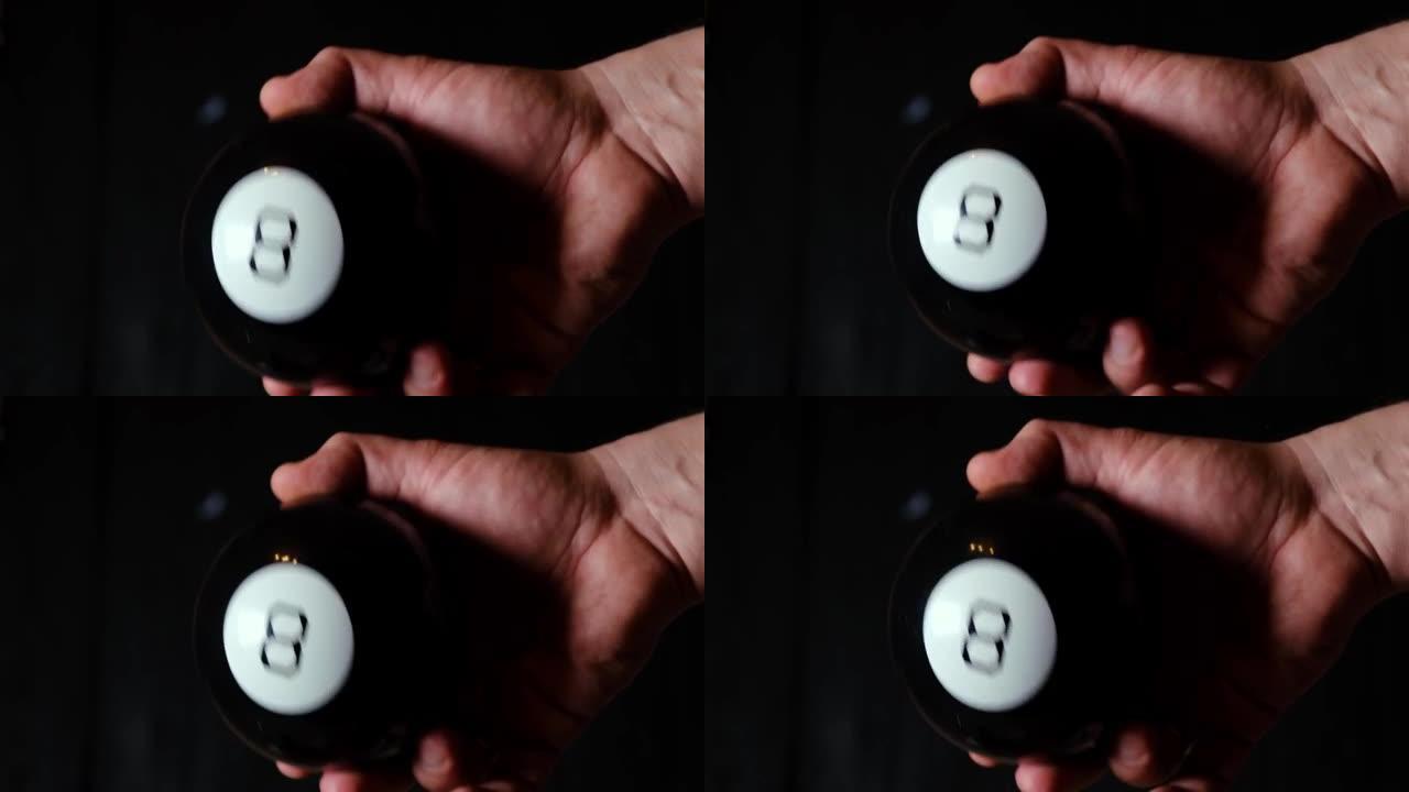 预测球数字八号在一个黑色背景上的人的手中。