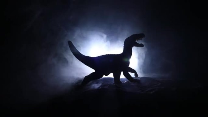 雾夜中巨型恐龙的剪影。带有小缩影的创意装饰。燃烧模糊的背景。选择性聚焦