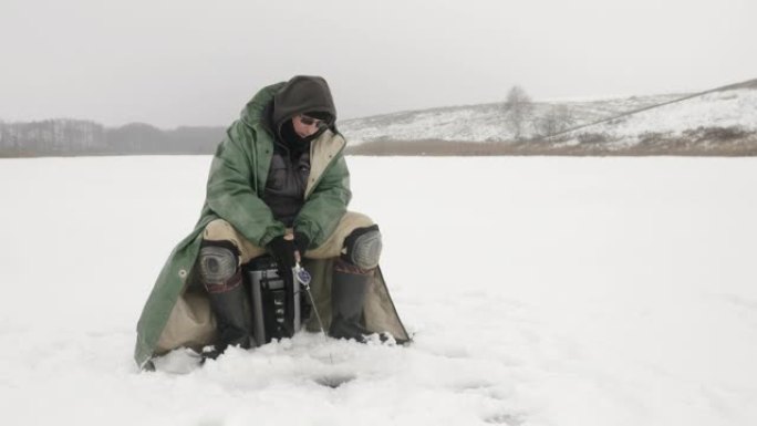 冬季钓鱼。渔夫正在冰洞里用鱼竿抓鱼。人类正在冰冻的湖上钓鱼。冬季极限装备。