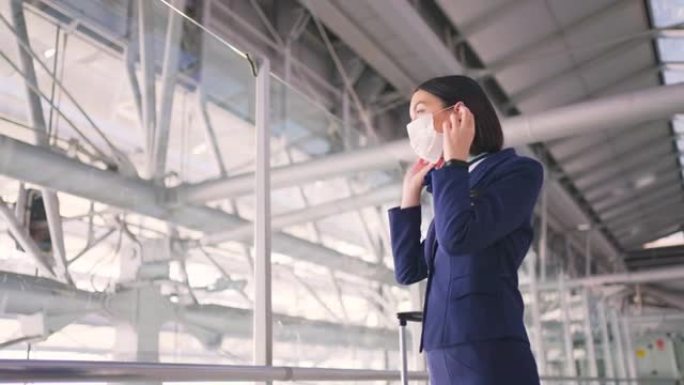 在COVID大流行期间，戴着口罩的空姐或空姐在机场候机楼走到飞机上，以防止冠状病毒感染。航空运输概念