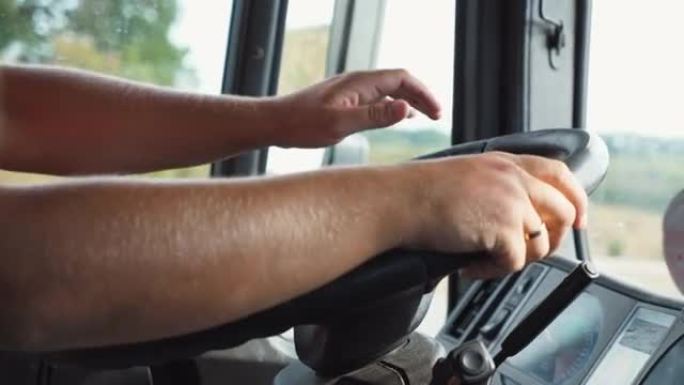 卡车司机的男性手握着一个大方向盘，同时在乡村操作卡车。卡车司机在乡间道骑行到目的地。物流和运输的概念