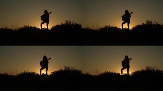 音乐家在日落时弹吉他的剪影，有日出或日落的音乐，大自然中的吉他，橙色的天空。4k慢动作