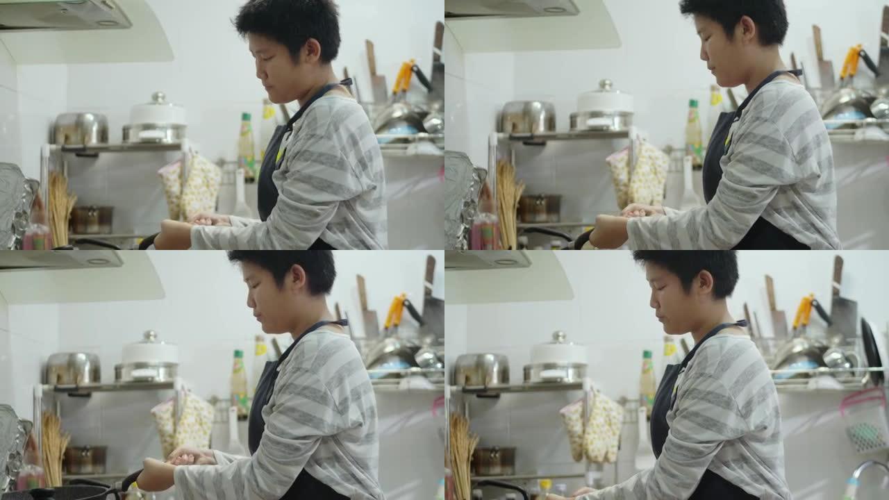 亚洲青春期男孩穿着围裙在厨房做爆米花，周末生活方式概念。