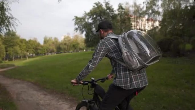 男性骑自行车的人带着透明背包的猫在山地自行车上旅行。宠物和男人的友谊，动物的爱。总是在一起。快乐踩踏