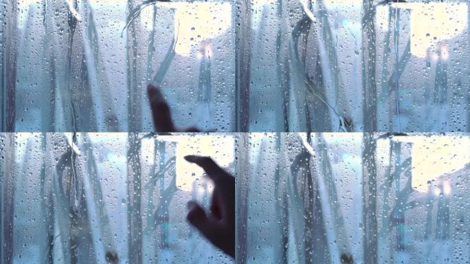 雨天，一只手在窗户的湿玻璃上画了一颗心。分离、爱、痛苦和折磨。雨滴落在玻璃上。水滴飞溅到玻璃上。水滴