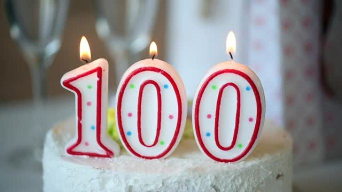 生日蜡烛作为100号在桌上的甜蛋糕上，100岁生日