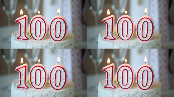 生日蜡烛作为100号在桌上的甜蛋糕上，100岁生日