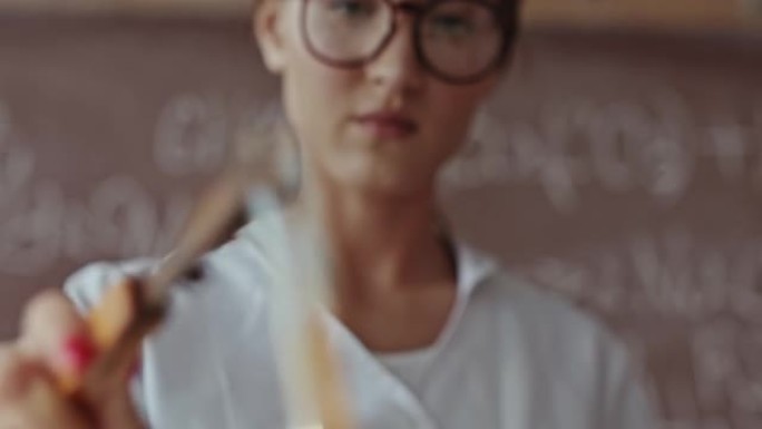 戴着眼镜的年轻女科学家在本生灯的明火上加热试管中的化学物质-特写