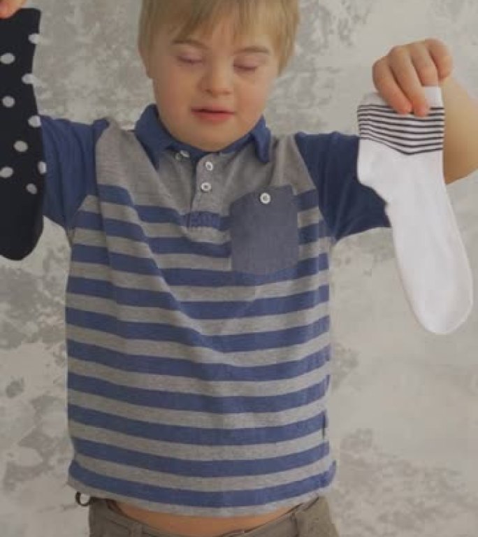 有袜子的唐氏综合症的可爱小男孩。垂直格式