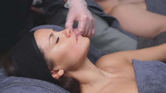 美容师为有魅力的女人做颊面部按摩。面部肌肉松弛的治疗方法。特写