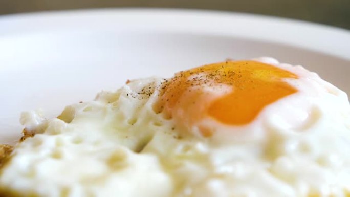 在盘子上撒上胡椒粉的烧鸡蛋和蛋黄的特写