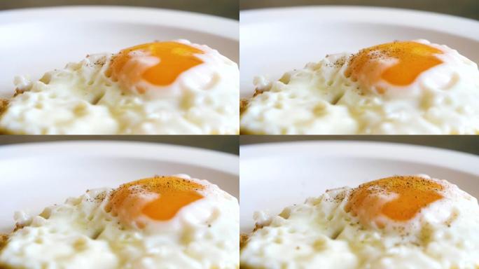 在盘子上撒上胡椒粉的烧鸡蛋和蛋黄的特写