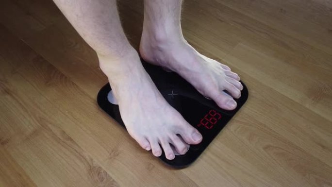 男人检查他的体重。秤上的腿。