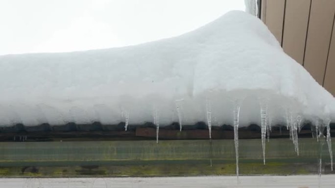 厚厚的白雪和屋顶侧面的悬冰