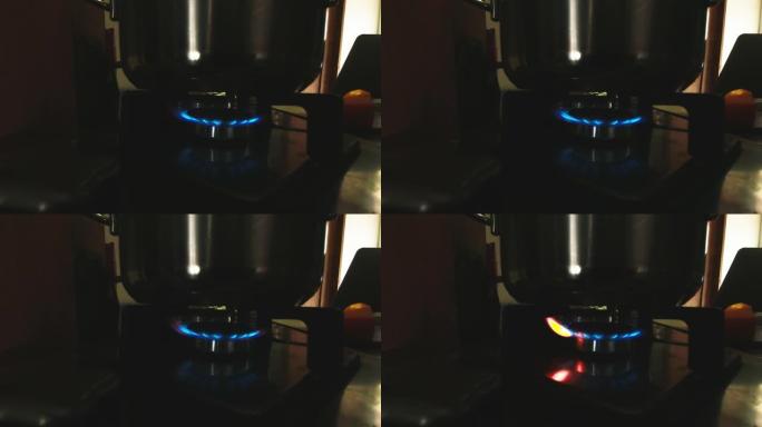 在家里昏暗的灯光下，用银锅燃烧的气体烹饪火焰的特写侧视图。准备食物和时间概念copyaste背景