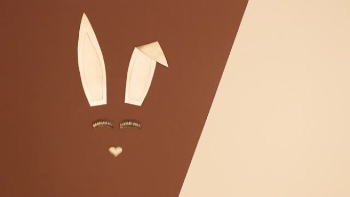 创意金色复活节兔子在裸色棕色背景上闪烁睫毛。停止运动