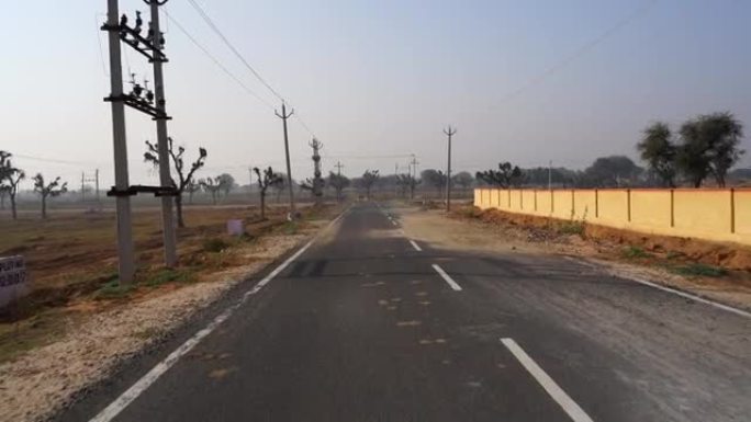 柏油路画面穿过空旷的田野。印度斋浦尔附近的农村道路高质量视频拍摄。