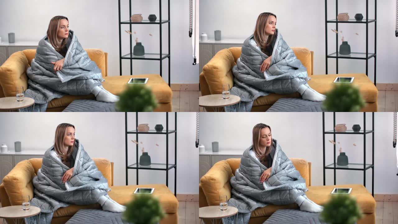 忧郁的孤独女性沉思在温暖的毯子包裹的沙发上。用4K红色相机拍摄
