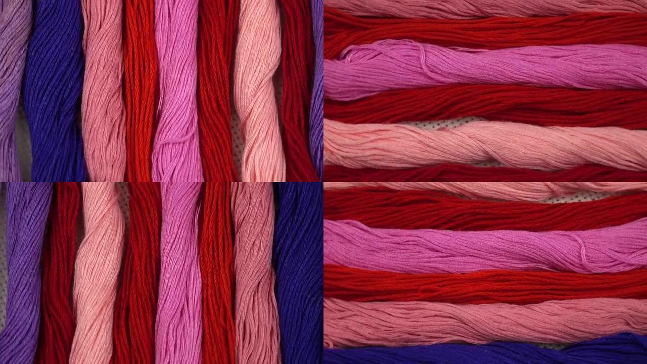 红色，粉红色和紫色调的绣花线排列在带有帆布的绣花环上
