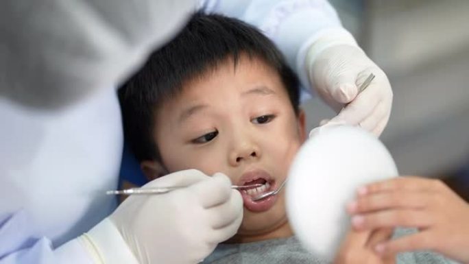 亚洲孩子在牙科诊所检查牙医。牙科检查和医疗保健的概念