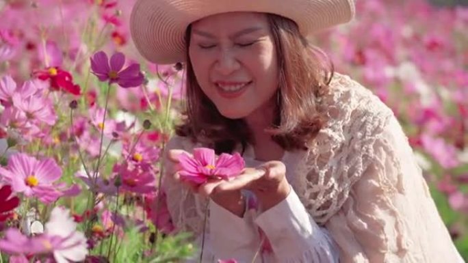 亚洲成熟女性在宇宙草地上休息的面部表情，闻到花朵的味道