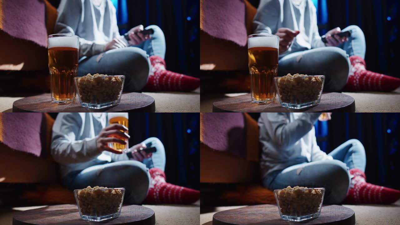 女人坐在地板上，看电视，喝啤酒和花生