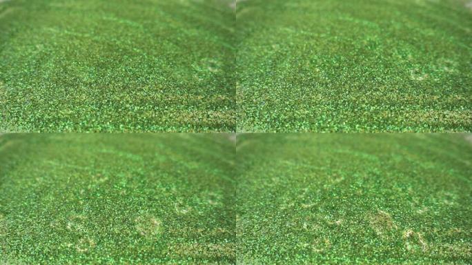 在慢动作中，液体滴落在由绿色小点组成的表面上。