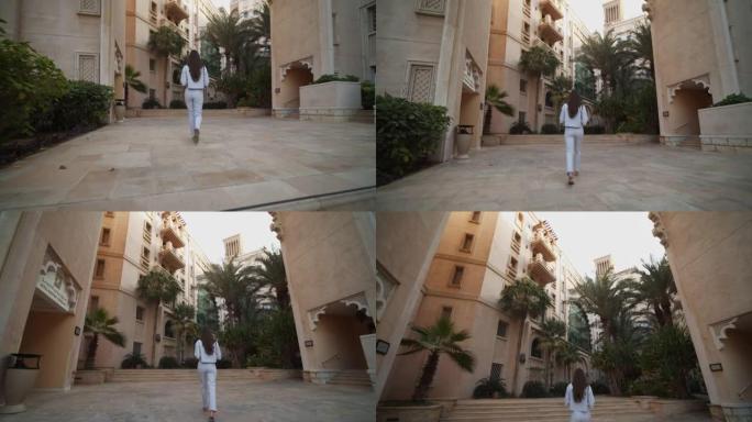 跟随一名妇女走过迪拜富裕的居民区。阿拉伯联合酋长国被豪华住宅包围的女游客的街景