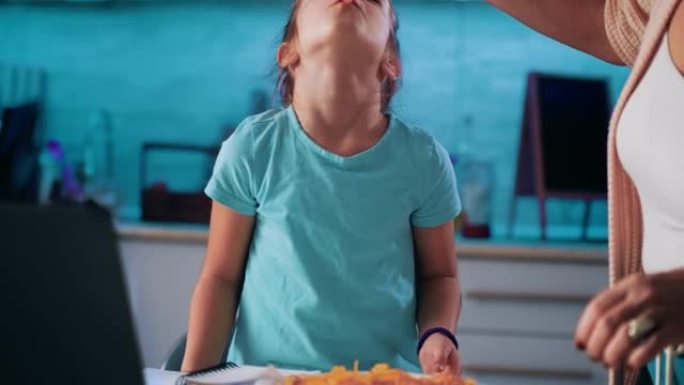 一个年轻女孩以有趣的方式吃意大利面，幸福和玩弄食物的镜头。母亲的手喂女孩意大利面